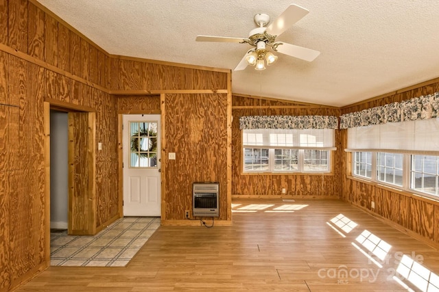 foyer featuring heating unit, wood walls, plenty of natural light, and lofted ceiling
