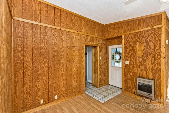 foyer featuring a textured ceiling, wooden walls, wood finished floors, and heating unit