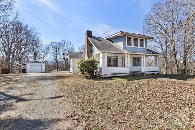 view of front of home featuring a detached garage, a chimney, a porch, driveway, and an outdoor structure