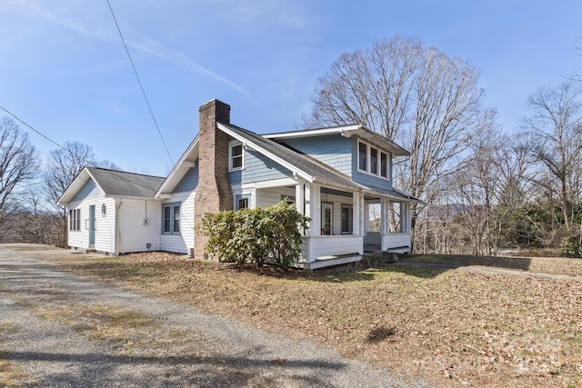view of home's exterior with driveway, a chimney, and a porch