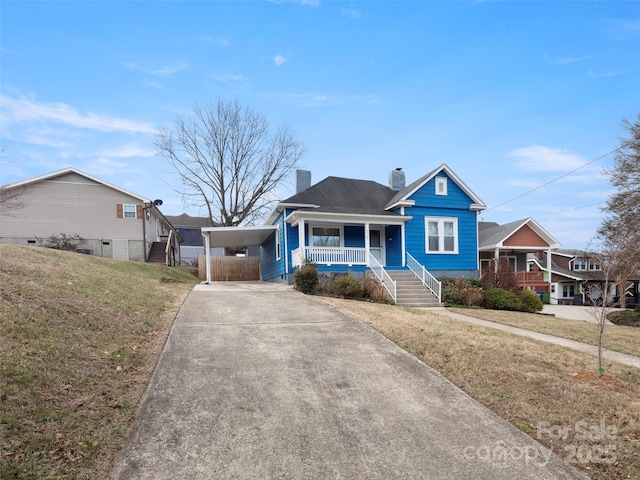 view of front of house featuring a carport, covered porch, and a front lawn