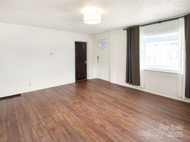 unfurnished room with crown molding, dark hardwood / wood-style floors, and a textured ceiling