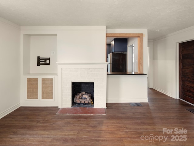 unfurnished living room with crown molding, a brick fireplace, dark wood-type flooring, and a textured ceiling