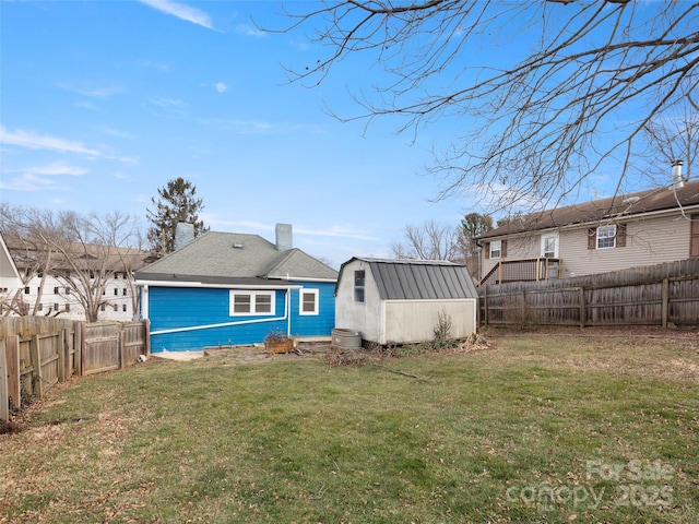 rear view of property with a yard and a storage unit