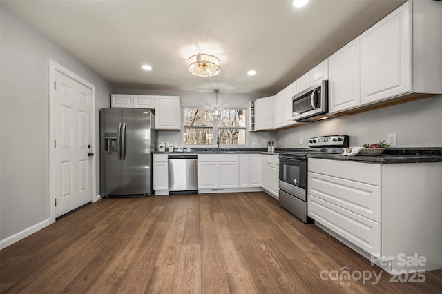 kitchen with appliances with stainless steel finishes, white cabinetry, sink, a chandelier, and dark hardwood / wood-style flooring