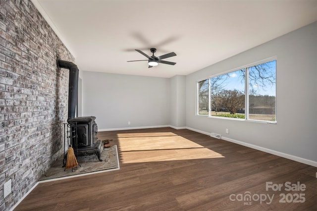 unfurnished living room featuring ceiling fan, a wood stove, and dark hardwood / wood-style flooring