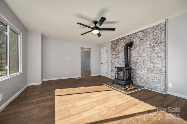 unfurnished living room with ceiling fan, dark hardwood / wood-style flooring, and a wood stove