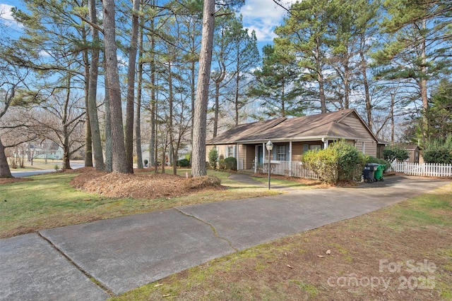 view of front of property with covered porch, fence, and a front lawn