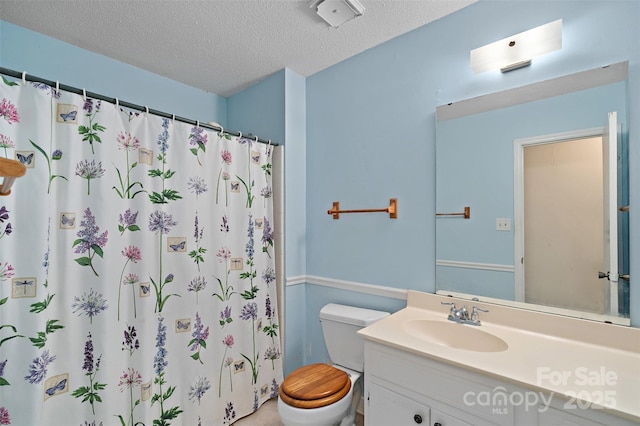 bathroom featuring a textured ceiling, curtained shower, vanity, and toilet