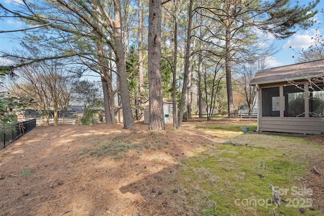 view of yard featuring a shed, fence, and an outbuilding