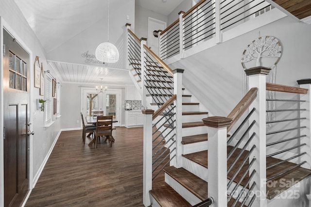 stairway featuring wood-type flooring, a notable chandelier, and high vaulted ceiling