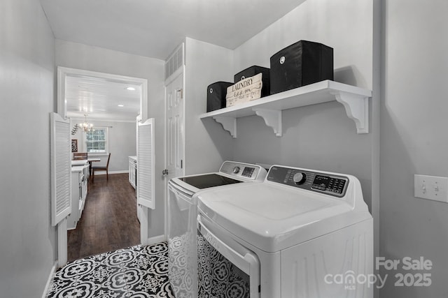 laundry room featuring dark hardwood / wood-style flooring, a notable chandelier, and washer and clothes dryer