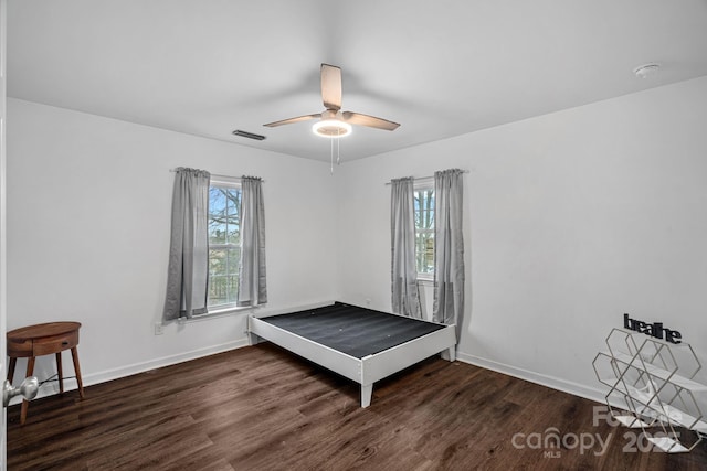 bedroom with multiple windows, dark hardwood / wood-style floors, and ceiling fan