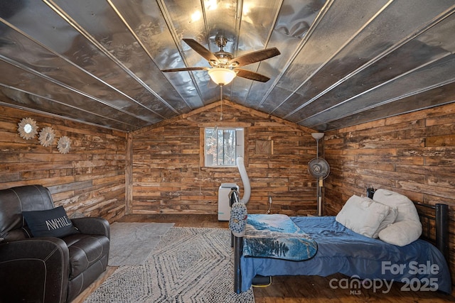 bedroom featuring hardwood / wood-style flooring, ceiling fan, lofted ceiling, and wooden walls