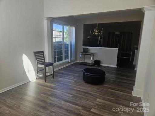 living area featuring ornate columns, dark wood-type flooring, and a notable chandelier