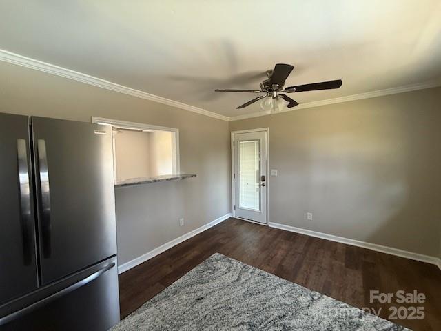 interior space featuring dark wood-type flooring, light stone counters, stainless steel refrigerator, ornamental molding, and ceiling fan