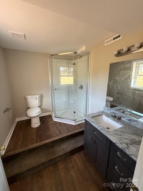 bathroom featuring a shower, wood-type flooring, vanity, and toilet