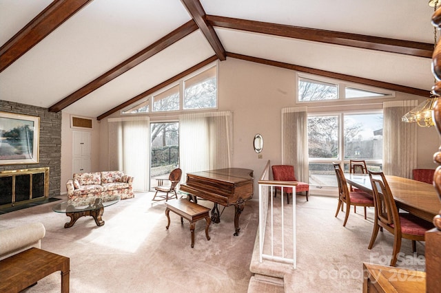 carpeted living room with beam ceiling, a stone fireplace, a wealth of natural light, and high vaulted ceiling