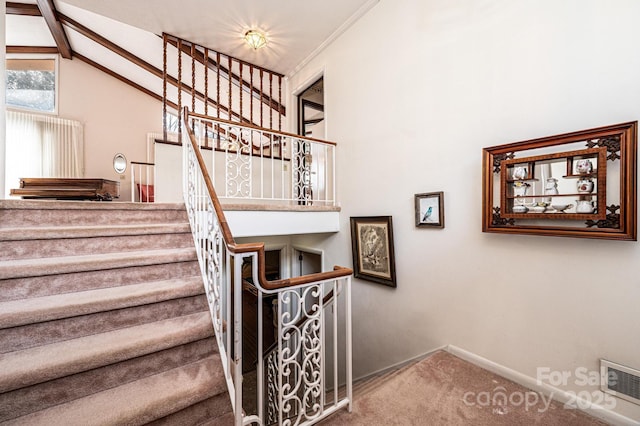 stairway with lofted ceiling with beams and carpet