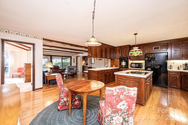 kitchen with a kitchen island, hanging light fixtures, black appliances, dark brown cabinets, and light wood-type flooring