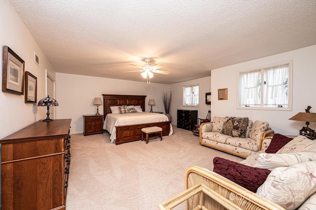 bedroom featuring light colored carpet, a textured ceiling, and ceiling fan