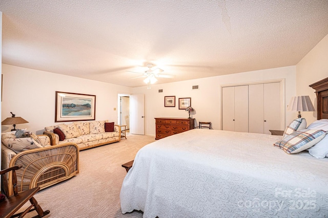 carpeted bedroom with ceiling fan, a closet, and a textured ceiling