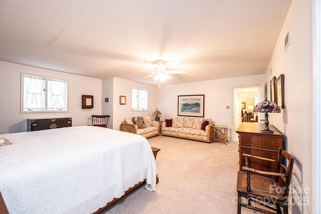 bedroom featuring ceiling fan, light carpet, and a textured ceiling