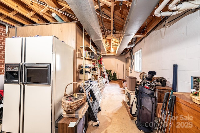 basement featuring white refrigerator with ice dispenser