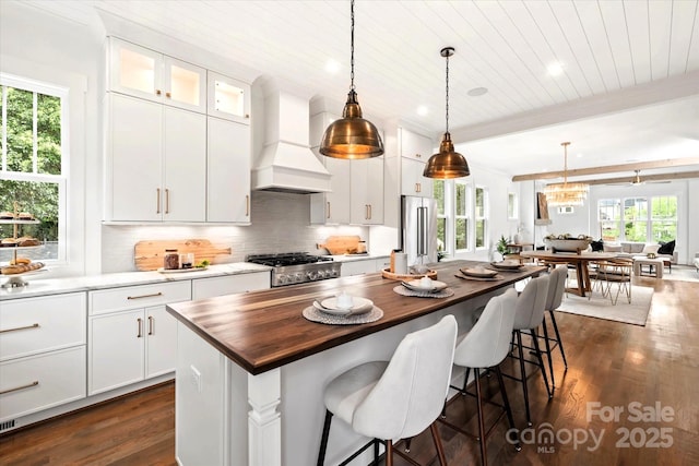 kitchen featuring range, custom range hood, a kitchen island, and white cabinets