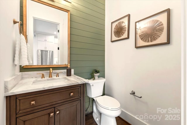 bathroom with vanity, toilet, and wood walls