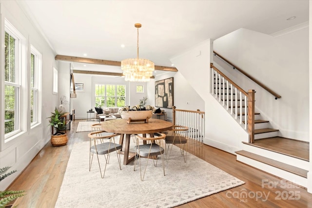 dining room with an inviting chandelier, ornamental molding, and light wood-type flooring