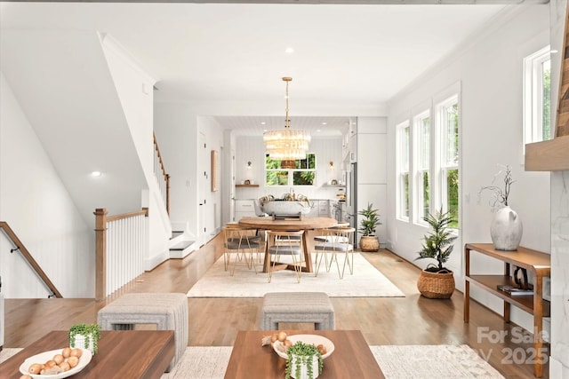 dining space with crown molding, light wood-type flooring, and a chandelier