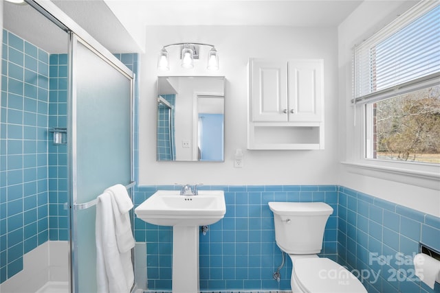 bathroom featuring toilet, an enclosed shower, sink, and tile walls