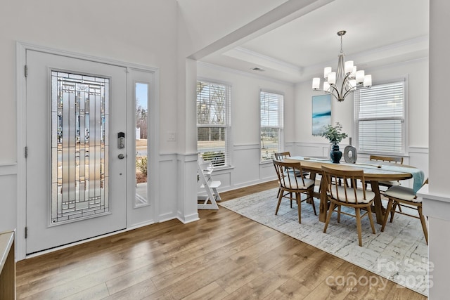 dining area with crown molding, a notable chandelier, a tray ceiling, and wood-type flooring