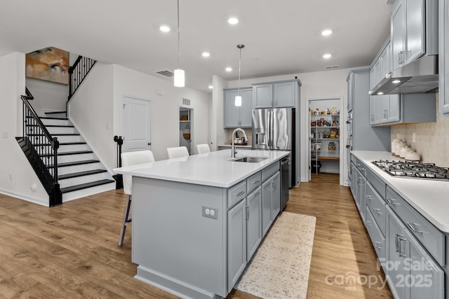 kitchen featuring pendant lighting, sink, a kitchen breakfast bar, a kitchen island with sink, and stainless steel appliances