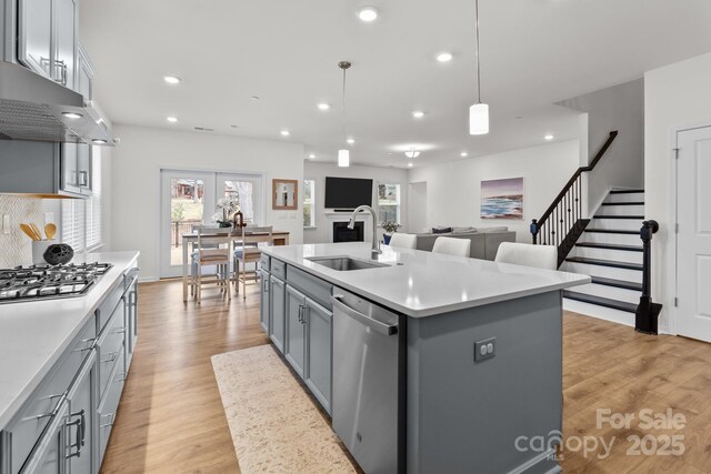 kitchen featuring appliances with stainless steel finishes, pendant lighting, sink, gray cabinetry, and a kitchen island with sink