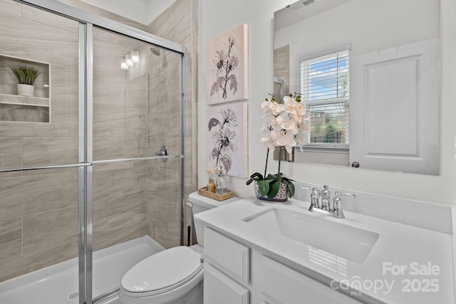 bathroom with vanity, toilet, and a shower with shower door