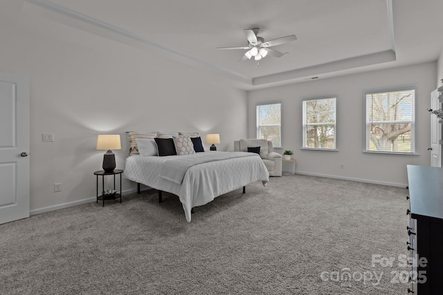 carpeted bedroom with ceiling fan and a tray ceiling