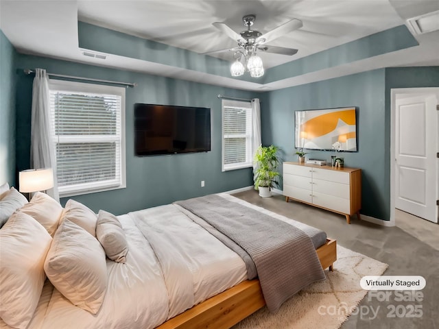 carpeted bedroom featuring multiple windows, a raised ceiling, and ceiling fan