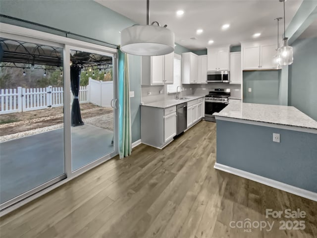 kitchen with decorative light fixtures, white cabinets, and appliances with stainless steel finishes