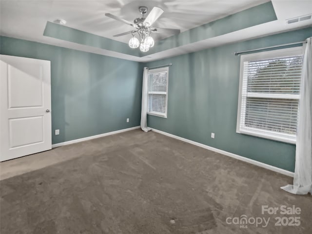 carpeted empty room featuring a raised ceiling and ceiling fan