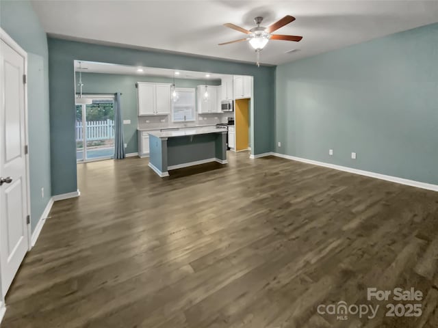 kitchen with dark wood-type flooring, ceiling fan, white cabinetry, stainless steel appliances, and a center island