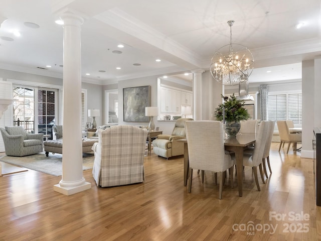 dining room featuring crown molding, a chandelier, decorative columns, and light hardwood / wood-style flooring