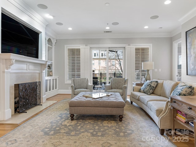 living room featuring hardwood / wood-style flooring, crown molding, and a premium fireplace