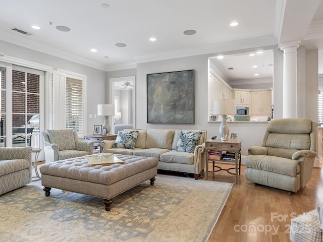 living room featuring decorative columns, crown molding, and light hardwood / wood-style flooring