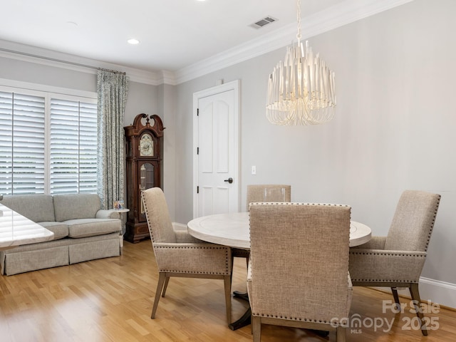 dining space with ornamental molding, a chandelier, and light hardwood / wood-style floors