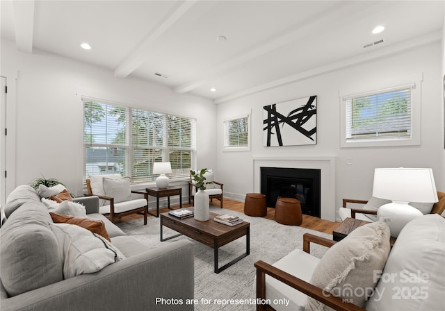 living area featuring recessed lighting, visible vents, light wood finished floors, beamed ceiling, and a glass covered fireplace