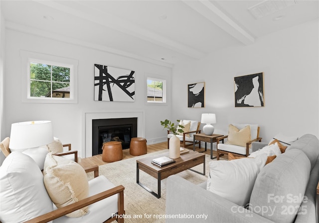 living room with a glass covered fireplace, wood finished floors, beam ceiling, and baseboards