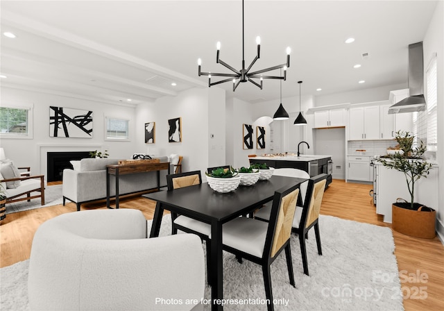 dining space with light wood finished floors, a fireplace, recessed lighting, and a healthy amount of sunlight