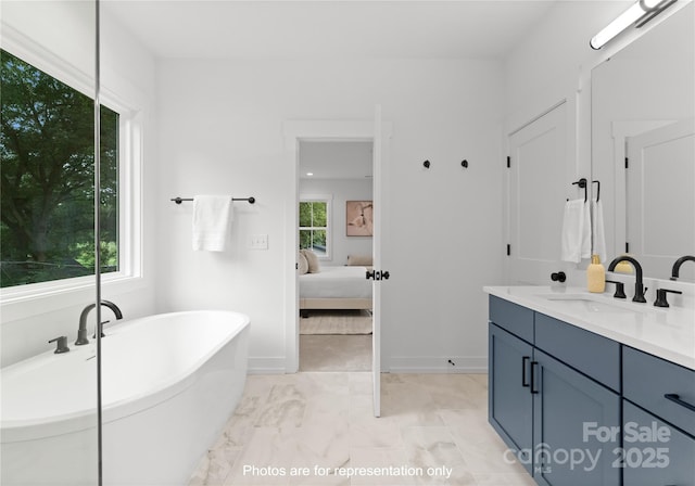 bathroom with ensuite bath, baseboards, a freestanding bath, and vanity